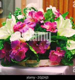 Bouquet von schönen künstlichen roten und weißen Blumen auf einem Hintergrund der Holzwand Stockfoto