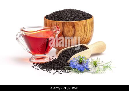 Schwarzes Kreuzkümmelöl in Soße und Nigella sativa-Blüten. Nigella sativa Samen in Holzlöffel isoliert auf weißem Hintergrund. Stockfoto