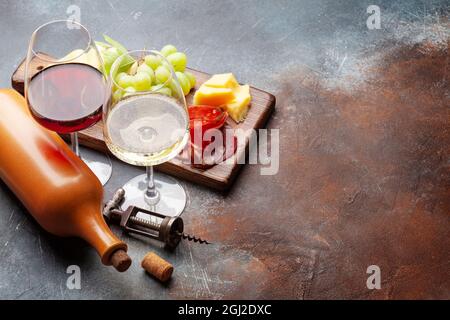 Weißweingläser und Rotweingläser, Weintrauben- und Vorspeisenbrett mit Käse und Prosciutto. Mit Kopierbereich Stockfoto