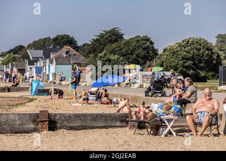 Sonnenanbeter auf ihren Strandhütten in Hamworthy, in der Nähe von Poole, Dorset, genießen die Mini-Hitzewelle im Herbst, England, Großbritannien Stockfoto