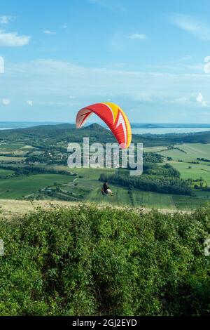 Gleitschirmfliegen über die Berge des Plattensees in Ungarn an einem Sommertag. Stockfoto