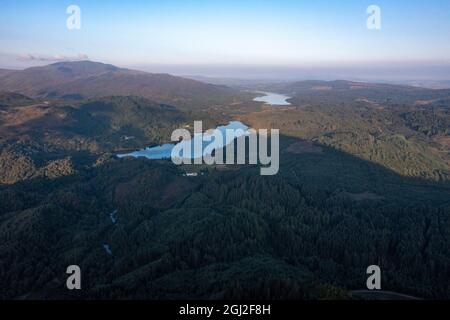 Ban Venue, Loch Achray, Loch Lomond und Trossachs National Park, Schottland. 7. September 2021 IM BILD: Drohnenansicht von Loch Achray aus und in der Ferne, Loch Venachar. Der Schatten von Ben Venue, der sich direkt hinter der Kamera und unter den immergrünen, von Wald bedeckten Ausläufern befindet und bei Tagesausflüglern und Forellen aus aller Welt beliebt ist. Quelle: Colin Fisher Stockfoto