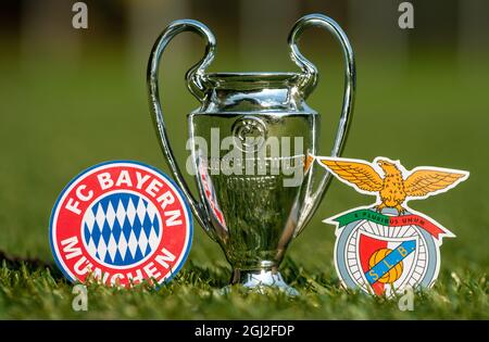 27. August 2021 München, Deutschland. Die Embleme der Fußballvereine FC Bayern München und S.L. Benfica und des UEFA Champions League Cup auf dem grünen Rasen o Stockfoto