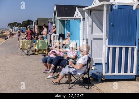 Sonnenanbeter auf ihren Strandhütten in Hamworthy, in der Nähe von Poole, Dorset, genießen die Mini-Hitzewelle im Herbst, England, Großbritannien Stockfoto