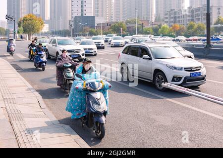 Menschen auf einem elektrischen Fahrrad mit farbenfroher Windschutzscheibe  an der Kreuzung, Hefei, China Stockfotografie - Alamy