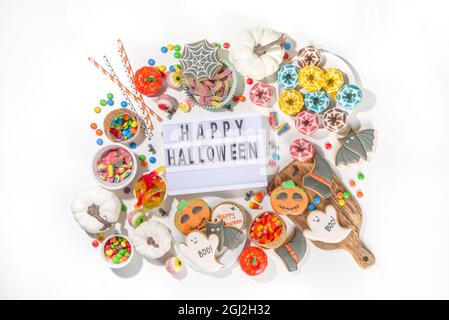 Set aus verschiedenen klassischen Halloween-Leckereien auf weißem Hintergrund. Auswahl Sortiment traditionelle Kekse, Lebkuchen, Süßigkeiten, Süßigkeiten und Deko-Kürbisse. Stockfoto