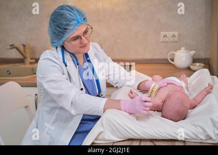 Der Arzt kämmt die Haare eines Neugeborenen. Krankenschwester in Uniform mit einem Kamm in der Hand für ein Kind Stockfoto