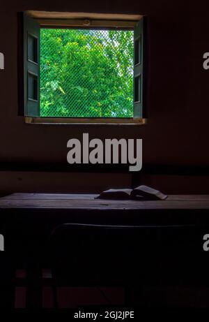 Ein offenes Buch auf einem Holztisch in der Nähe eines Fensters in einem Bauernhaus in der Nähe der Stadt Arcabuco im Zentrum Kolumbiens. Stockfoto