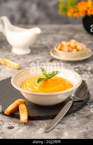 Cremiges Karotten- und Kürbispüree auf grauem Steingrund. Selektiver Fokus. Stockfoto