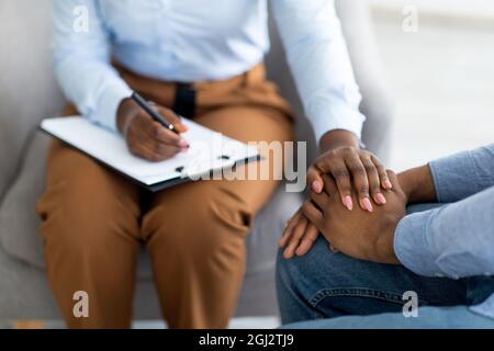Nicht erkennbarer Psychotherapeut, der depressive männliche Patienten unterstützt, seine Hände im medizinischen Büro berührt, Nahaufnahme. Berater tröstet jungen Kerl mit m Stockfoto