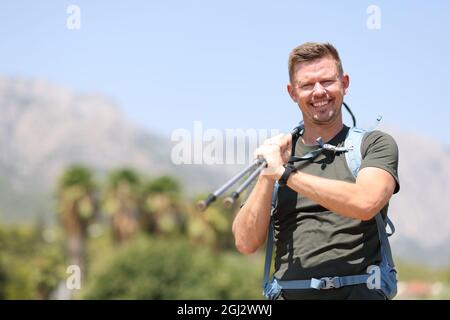 Lächelnder Mann, der skandinavische Stöcke in der Nähe des Berges hält Stockfoto