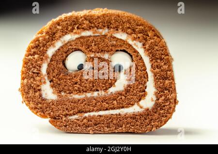 Schokoladen-Biskuitrolle mit Vanillegeschmack, Füllung mit dekorieren süßen Augen, Schokolade schweizer Rolle, lustiges Essen Stockfoto