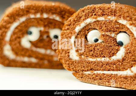 Schokoladen-Biskuitrolle mit Vanillegeschmack, Füllung mit dekorieren süßen Augen, Schokolade schweizer Rolle, lustiges Essen Stockfoto