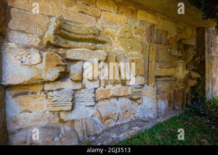 Fragmente der geschnitzten Steinarbeiten der Hailes Abbey, eingebettet in die Wand des Friedhofs der St. Peter’s Church neben dem Stanway House, Cotswolds, England Stockfoto