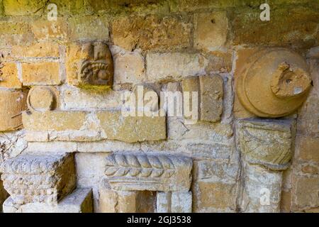 Fragmente der geschnitzten Steinarbeiten der Hailes Abbey, eingebettet in die Wand des Friedhofs der St. Peter’s Church neben dem Stanway House, Cotswolds, England Stockfoto