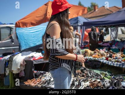 Sokobanja, Serbien, 19. Aug 2021: Eine junge Frau mit rotem Hut steht neben Ständen auf einem Dorfmarkt Stockfoto