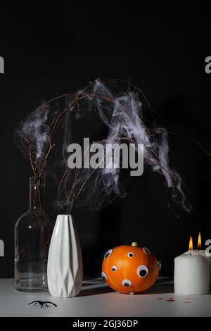 halloween Tag Komposition.Party Grußkarte.Kürbis mit Augen, Kerze und trockenem Zweig mit Spinnennetz auf schwarzem Hintergrund.Kreatives halloween-Konzept Stockfoto