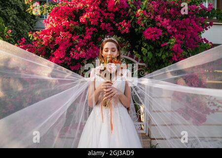 Braut mit weißem Hochzeitskleid mit bunten und getrockneten Brautstrauß mit roten Bougainvillea Hintergrund. . Hochwertige Fotos Stockfoto