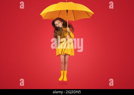 Glücklich emotionale Mädchen lachen mit Regenschirm auf rotem Hintergrund. Herbst, Frühjahrssaison. Stockfoto