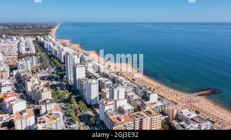 Schöne Luftbilder der portugiesischen Touristenstadt Quarteira. An der Küste während der Strandsaison mit Touristen, die sich sonnen. Stockfoto