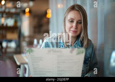 Frau schaut sich die Speisekarte im Restaurant an. Stockfoto