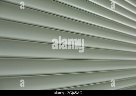 Jalousien-Struktur auf der Straße. Kunststoffoberfläche für die Fenster. Gerippte lange Lamellen. Grauer Hintergrund aus industriellem Material. Stockfoto