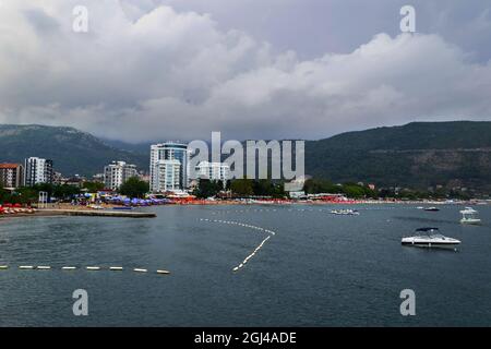 Nahaufnahme der Stadt Budva von einer Yacht aus, im Hintergrund eine Bergkette mit Vegetation. Reise in Montenegro auf dem Seeweg. Stockfoto