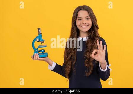 Wissenschaft und Kindheit. Jugendliches Mädchen präsentiert Mikroskop. Zurück zur Schule. Biologie studieren, Stockfoto