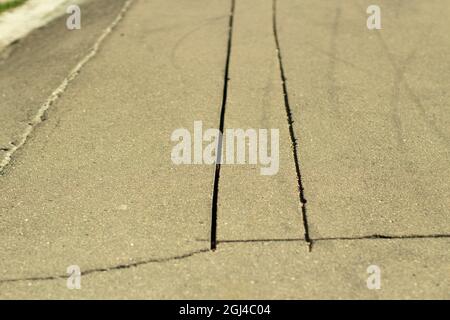 Schlitze auf dem Asphalt. Asphalt auf der Straße gesägt. Zwei Risse. Eine Materialprobe auf der Autobahn. Stockfoto