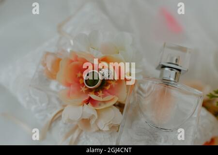 Blume mit einem Paar Eheringe und Parfüm auf dem Tisch Stockfoto