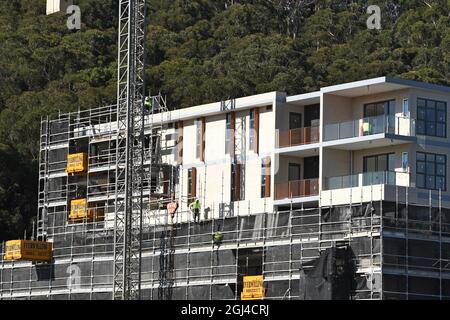 Gosford, NSW, Australien - 15. Juli 2021: Arbeiter demontieren Sicherheitsnetze und Gerüste in den nun fertiggestellten oberen Stockwerken des neuen sozialen Wohnungsbaus bei Stockfoto