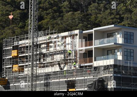 Gosford, NSW, Australien - 15. Juli 2021: Arbeiter demontieren Sicherheitsnetze und Gerüste in den nun fertiggestellten oberen Stockwerken des neuen sozialen Wohnungsbaus bei Stockfoto