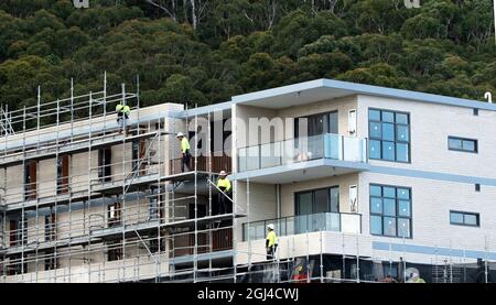 Gosford, NSW, Australien - 15. Juli 2021: Arbeiter demontieren Sicherheitsnetze und Gerüste in den nun fertiggestellten oberen Stockwerken des neuen sozialen Wohnungsbaus bei Stockfoto