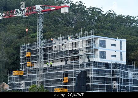 Gosford, NSW, Australien - 15. Juli 2021: Arbeiter demontieren Sicherheitsnetze und Gerüste in den nun fertiggestellten oberen Stockwerken des neuen sozialen Wohnungsbaus bei Stockfoto