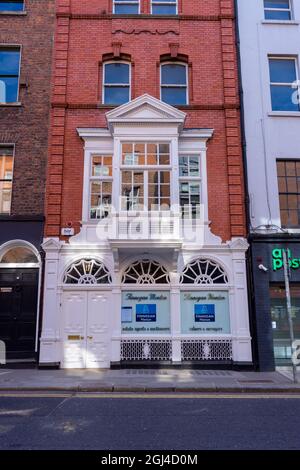 DUBLIN, IRLAND - 03. März 2021: Eine szenische Aufnahme eines Gebäudes aus roten Backsteinen mit weißen Türen und einem Balkon in Dublin, Irland Stockfoto