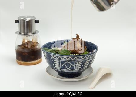 Frisch zubereiteter traditioneller vietnamesischer Pho mit Ochsenschwanz, heiß in einer Schüssel und Eiskaffee zum Trinken. Stockfoto