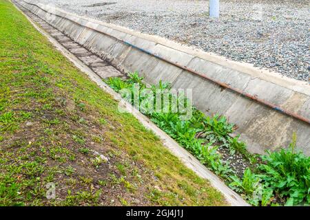 Der Industriekanal zur Ableitung von Regenwasser und zum Schutz vor Hochwasser wurde von dem Gras, mit dem es bewachsen war, zur Hälfte gereinigt Stockfoto