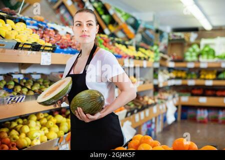 Junge Verkäuferin und Verkäufer halten die Hälfte der Wassermelone in der Hand Stockfoto