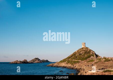 Der genuesische Turm und Leuchtturm bei Pointe de la Parata und Les Iles Sanguinaires bei Ajacio auf Korsika unter tiefblauem Himmel Stockfoto