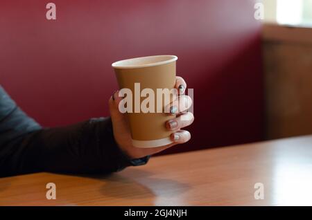 Person, die Kaffee im Café trinkt. Mädchen, das einen Kaffee nimmt. Trinken Sie Kaffee in einem Café Stockfoto