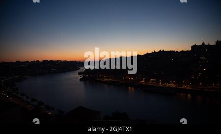Niedriger Sonnenuntergang mit Gradient - Orange Grün Gelb Blau - Stadt in Aussicht entlang des Flusses in Porto Portugal Stockfoto