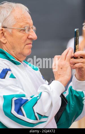 MOSKAU, RUSSLAND - 13. August 2021: Seitenansicht eines älteren Mannes, der auf seinem Smartphone tippt Stockfoto