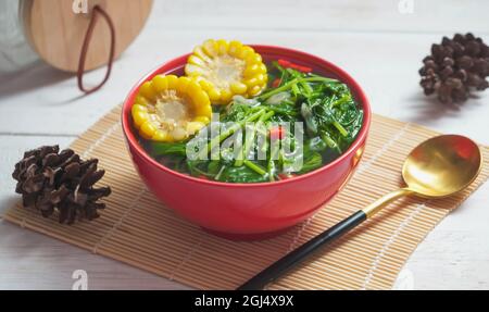 Bekannt als Sayur bening Bayam oder Spinat klare Suppe ist indonesische Lebensmittel aus Spinat, Karotten, Mais und anderen Gemüse. Serviert auf einer roten Schüssel Stockfoto