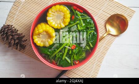 Bekannt als Sayur bening Bayam oder Spinat klare Suppe ist indonesische Lebensmittel aus Spinat, Karotten, Mais und anderen Gemüse. Serviert auf einer roten Schüssel Stockfoto