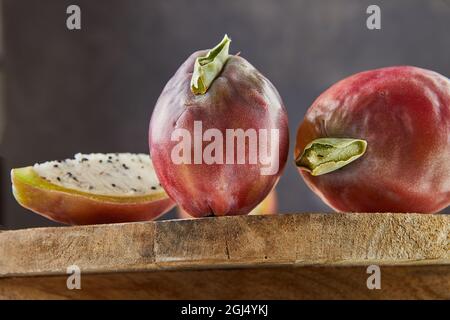 Peruanische Apfelkaktus Früchte ganz und auf Holzständer auf grauem Brett geschnitten. Wissenschaftlicher Name Cereus repandus. Stockfoto