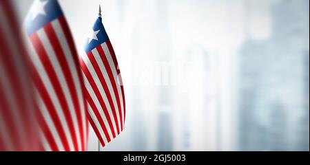 Kleine Flaggen von Liberia auf einem verschwommenen Hintergrund der Stadt Stockfoto