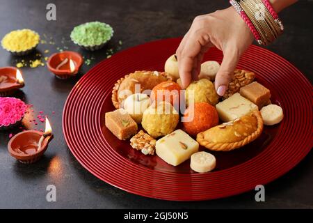 Indische Frau nimmt Diwali Süßigkeiten Gujiya peda barfi Indische süße Dessert mithai Festival Gericht Dussehra Holi ganesh chaturthi RAM navami Durga pooja Stockfoto