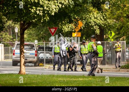 Richmond, VA, USA, 8. September 2021. Im Bild: Soldaten des Staates Virginia eskortieren Japhari Jones von Richmond aus dem verbarrikadierten Bereich, während die Statue des konföderierten Generals Robert E. Lee von seinem riesigen Sockel auf der Monument Avenue entfernt wird. Das oberste Gericht von Virginia entschied letzte Woche, dass das sechsstöckige Denkmal entfernt werden könnte. Es muss noch entschieden werden, ob das mit Anti-Rassismus-Graffiti bedeckte Podest angesichts seiner prominenten Rolle beim Anti-Rassismus-Aufstand von 2020 in Richmond entfernt wird. Kredit: Allison Bailey / Alamy Live Nachrichten Stockfoto