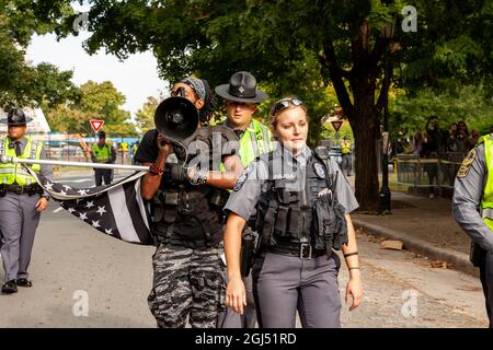 Richmond, VA, USA, 8. September 2021. Im Bild: Pajda, Polizeibeamter von Richmond, und die Soldaten des Staates Virginia eskortieren Japhari Jones aus Richmond aus dem verbarrikadierten Bereich, während die Statue des konföderierten Generals Robert E. Lee von seinem riesigen Sockel auf der Monument Avenue entfernt wird. Das oberste Gericht von Virginia entschied letzte Woche, dass das sechsstöckige Denkmal entfernt werden könnte. Es muss noch entschieden werden, ob das mit Anti-Rassismus-Graffiti bedeckte Podest angesichts seiner prominenten Rolle beim Anti-Rassismus-Aufstand von 2020 in Richmond entfernt wird. Kredit: Allison Bailey / Alamy Live Nachrichten Stockfoto