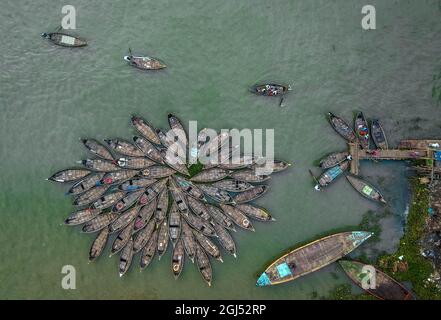 Aus der Vogelperspektive sehen Hunderte von Holzbooten wie Blumen im Buriganga River Port aus. Die mit bunt gemusterten Teppichen geschmückten Boote transportieren Arbeiter aus den Außenbezirken der Stadt zu ihrem Schicksal. Der Buriganga-Fluss wird täglich als Route in die Stadt Dhaka für Millionen von Arbeitern genutzt. Am 9. September 2021 in Dhaka, Bangladesch. (Foto von Mustasinur Rahman Alvi / Eyepix Group) Stockfoto